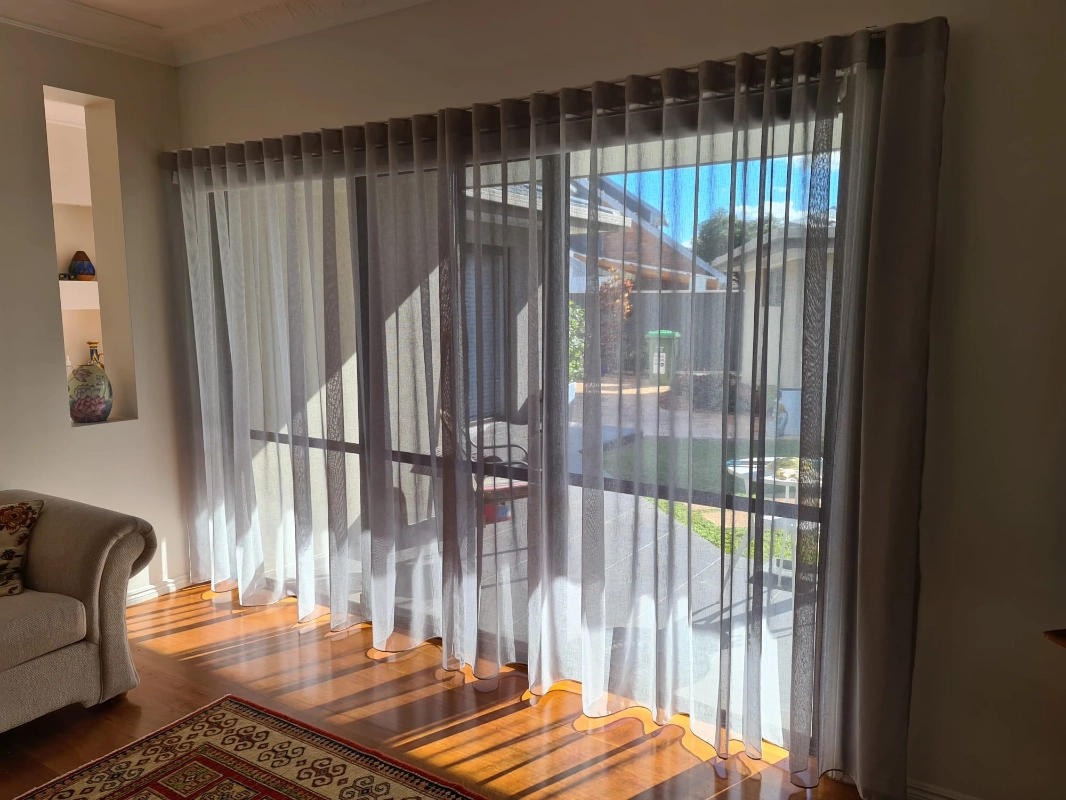 Sheer curtains filtering coastal light across a balcony doorway