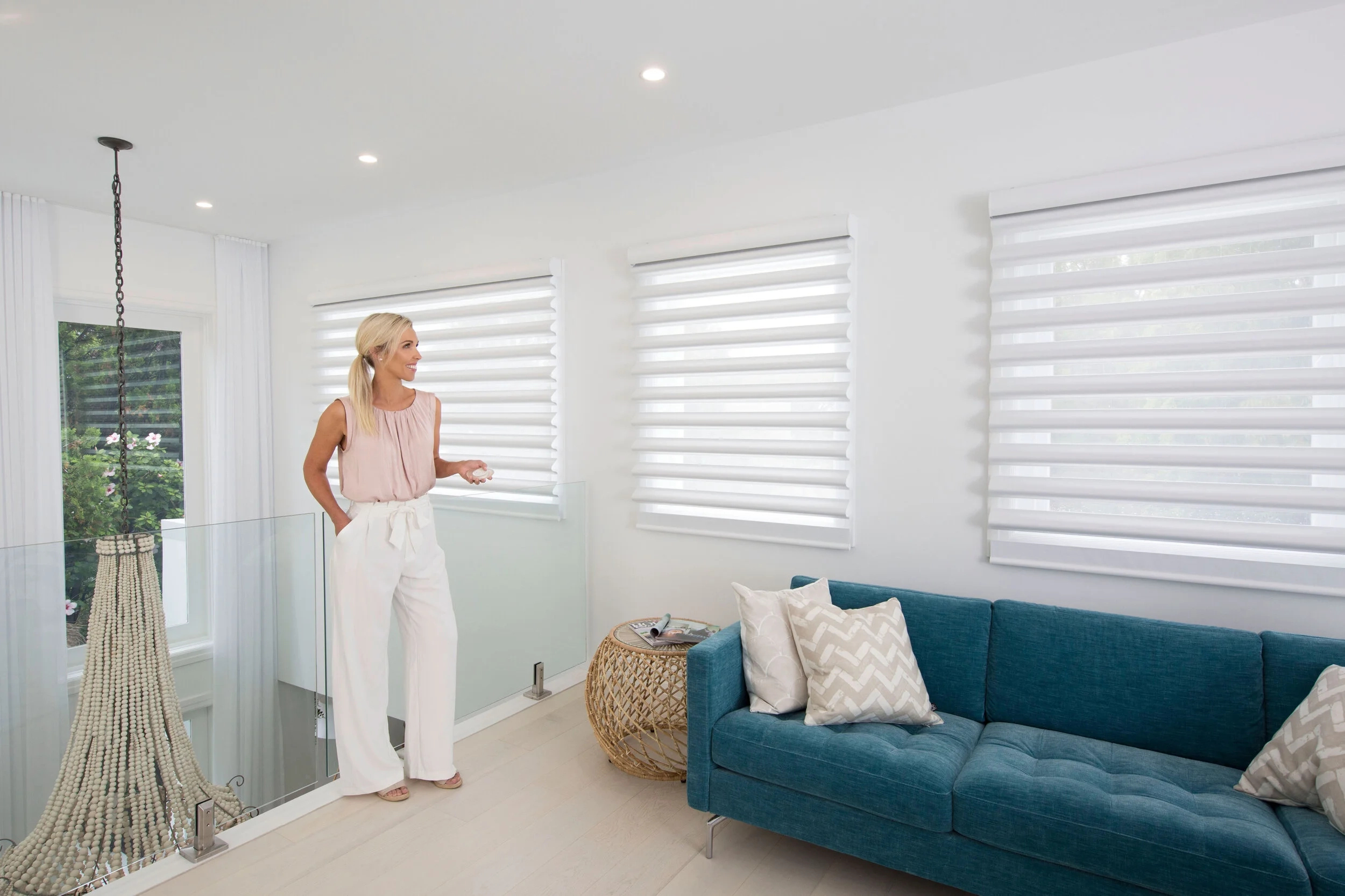 Woman using a controller for motorised blinds in a bright living room