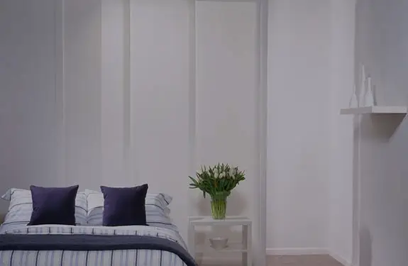 Panel blinds used as a soft room divider behind a bedroom sitting area