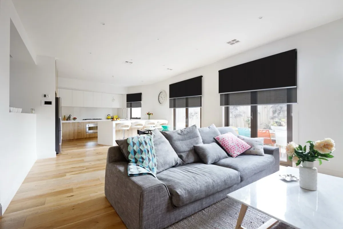 Double roller blinds combining black blockout and grey sunscreen layers in a living room