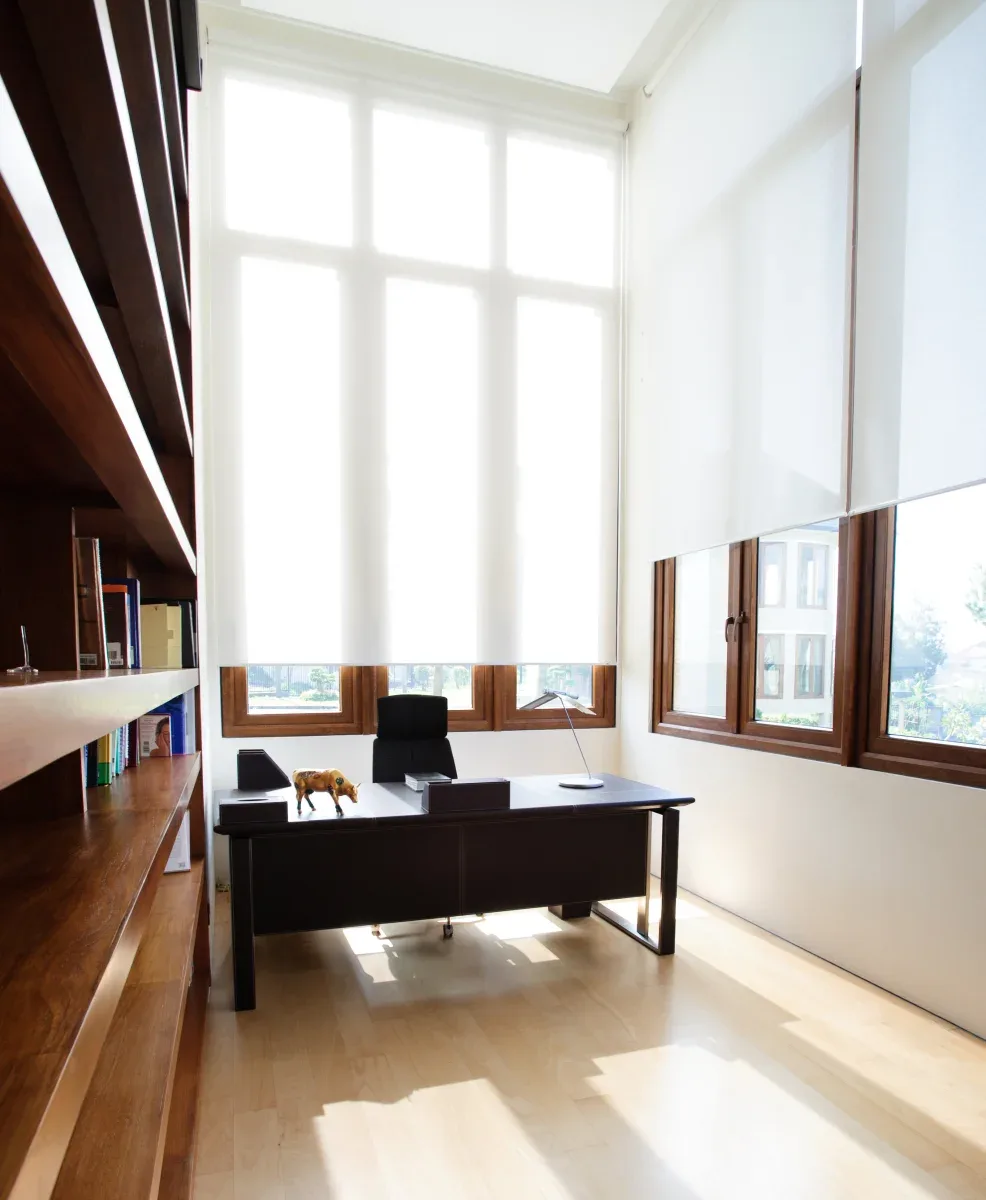 White sunscreen roller blinds fitted across tall office windows