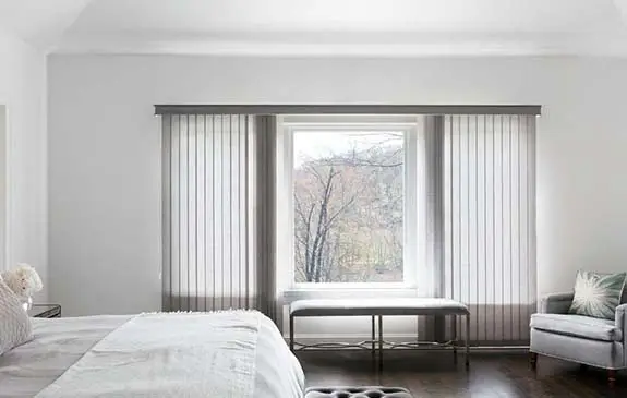 Vertical blinds tilted across a bedroom window for light control